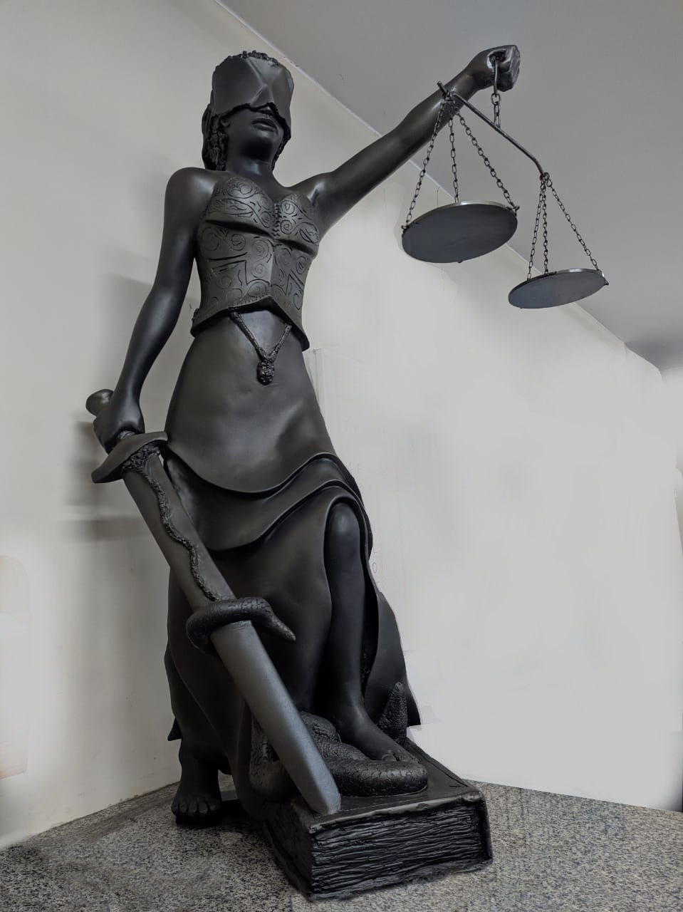 Escultura da Justiça com venda, espada e balança.