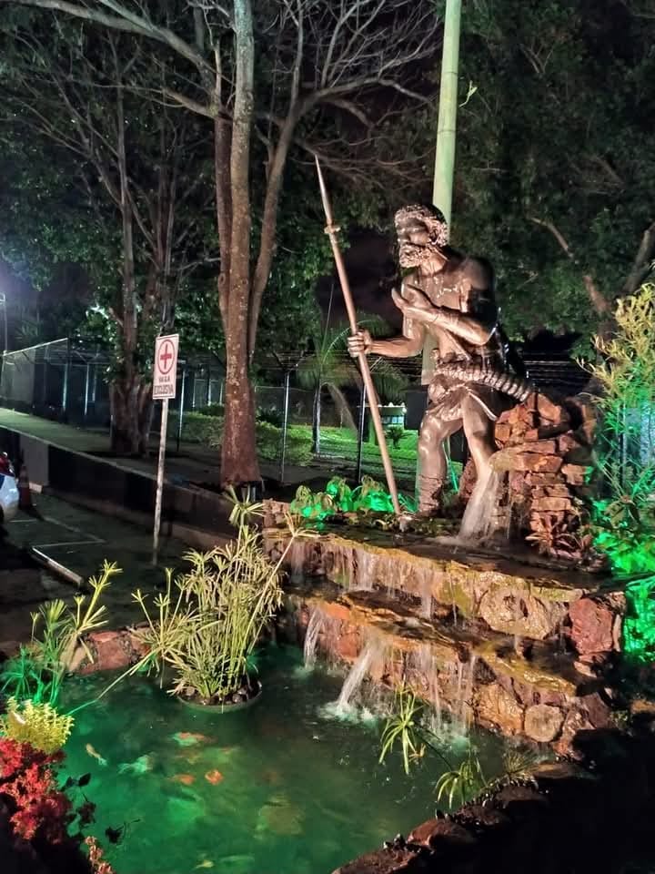 Escultura em um jardim iluminado à noite.